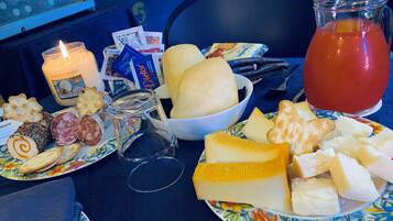 A table with various cheeses, crackers, a candle, and a pitcher of juice.