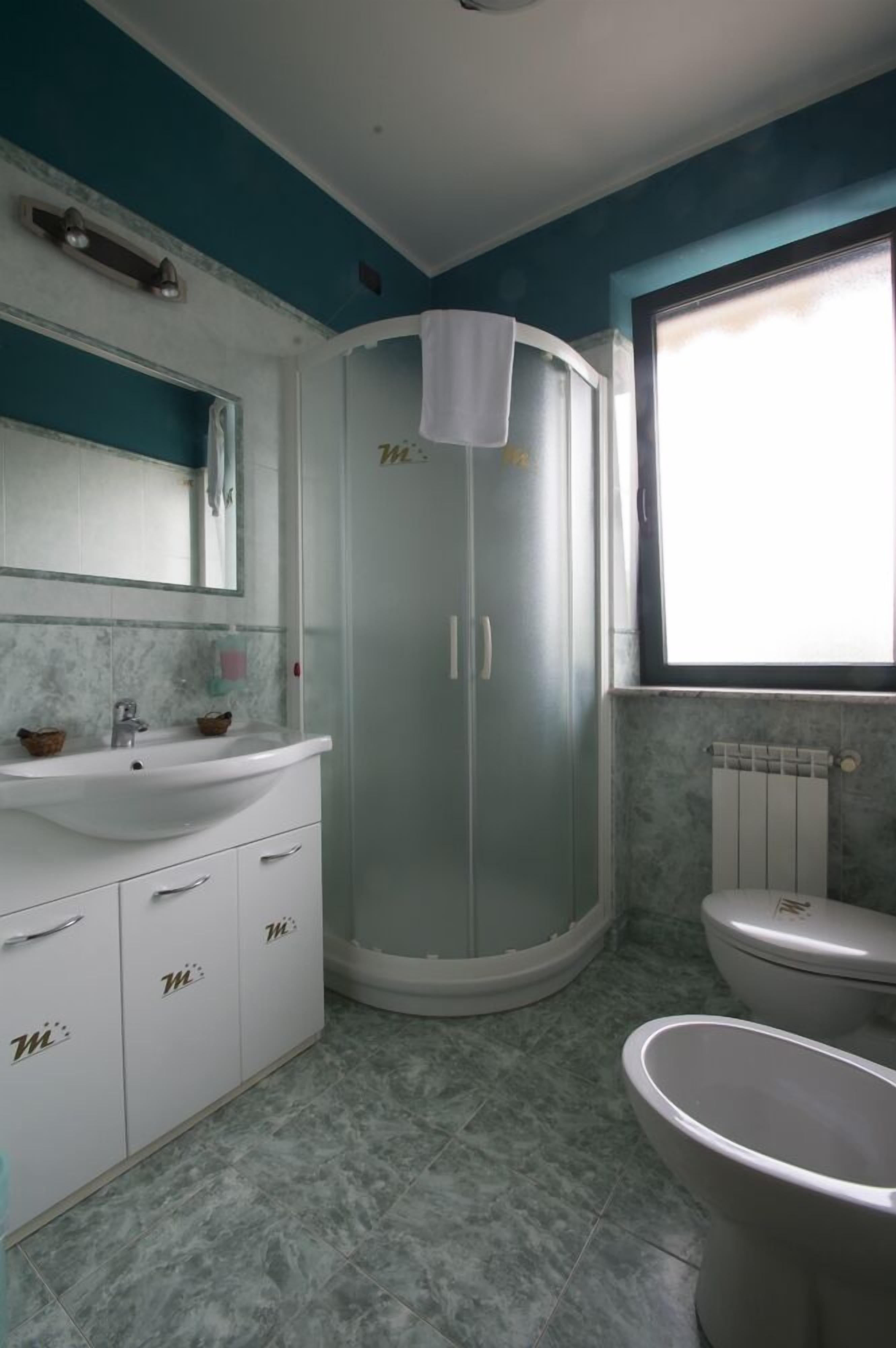 A bathroom with a white sink, a mirror, a white toilet, and a shower enclosure.