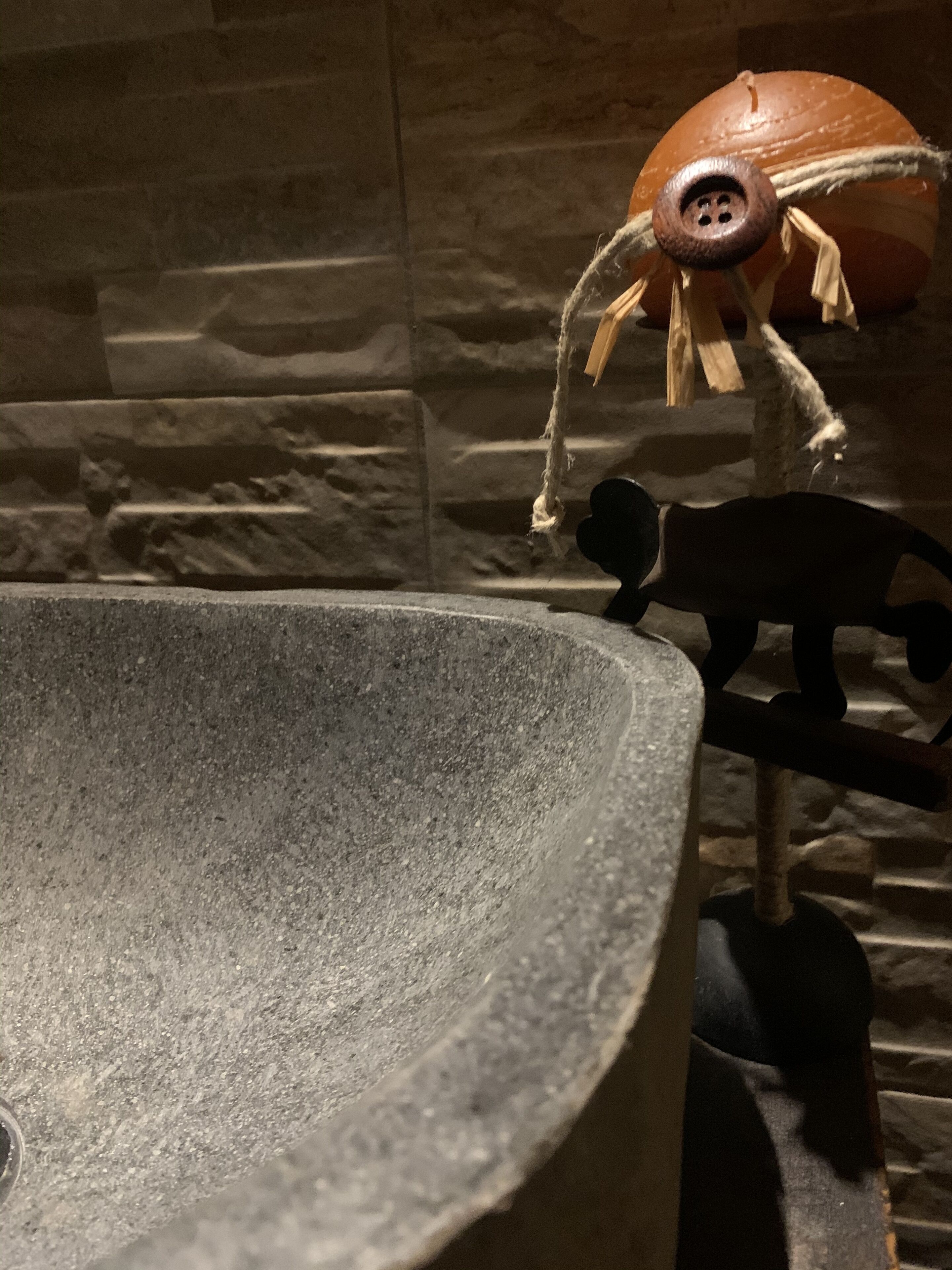 A stone basin with a rustic wooden figure and a small animal figure.