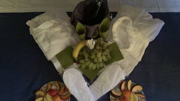 Una mesa con una botella de champán, un plátano, uvas y frutas cortadas.