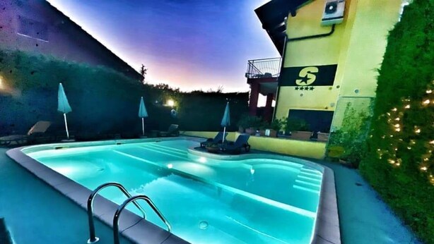 A swimming pool with a sunken hot tub, surrounded by lounge chairs and umbrellas, against a building with a '5' rating sign. - Hotel Residence S (Front)