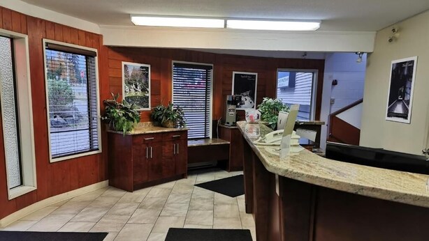 A reception area with a wooden counter, a coffee machine, and potted plants. - Hope Inn and Suites (Hope)