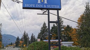 A sign for Hope Inn & Suites with a mountain backdrop. - Hope Inn and Suites (Hope)