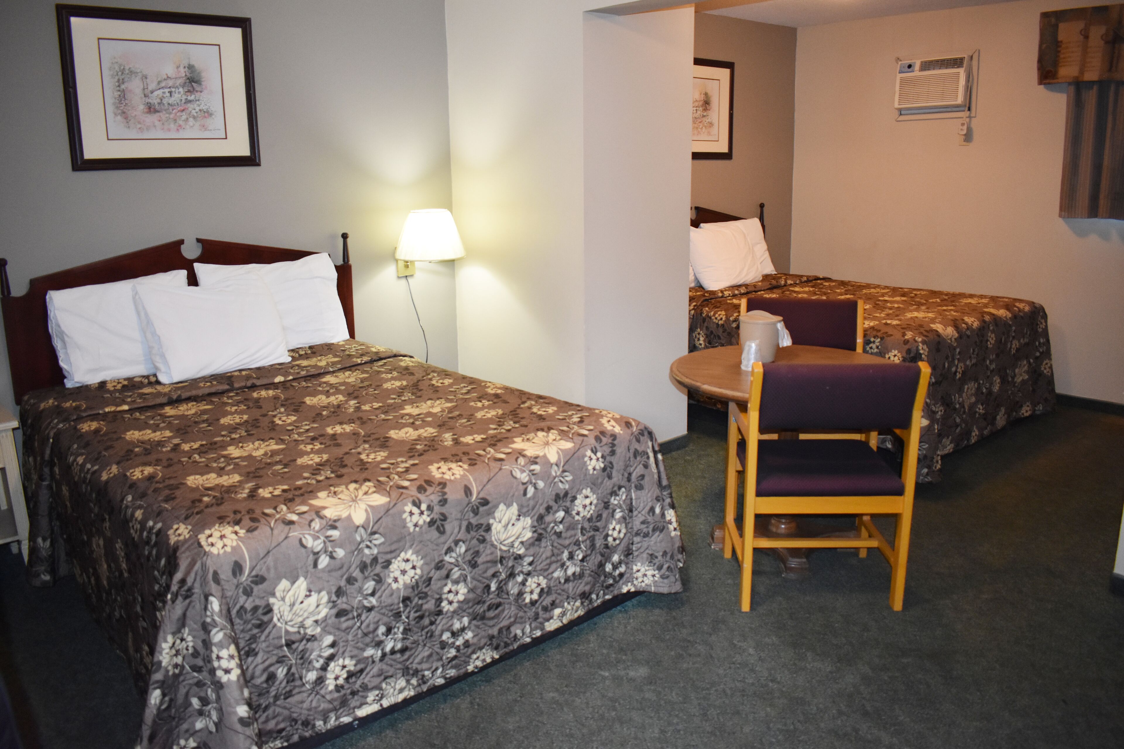 A hotel room with two beds, a desk, and a chair.