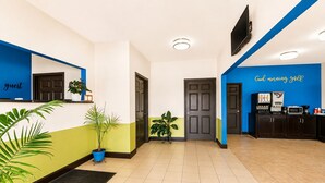 Zona de recepción de un hotel con mostrador, máquina de café y televisor instalado en la pared.