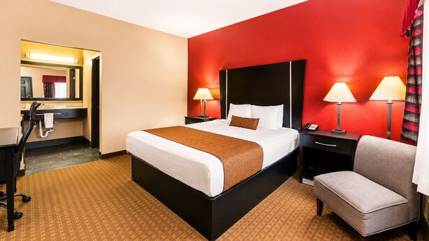 Una habitación de hotel con una cama, mesitas de noche, un escritorio y una silla.