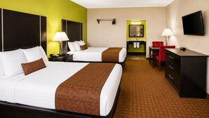 A hotel room with two beds, a desk, a dresser, a television, and a bathroom visible through an open door.