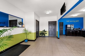 A hotel lobby with a reception desk, a coffee machine, and a TV mounted on the wall. - Rodeway Inn (Dilley)