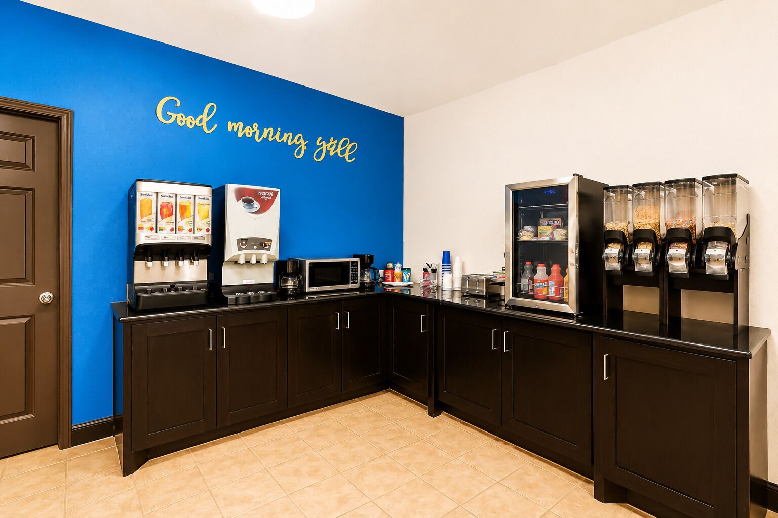A kitchen area with a coffee station, a microwave, and a beverage dispenser.
