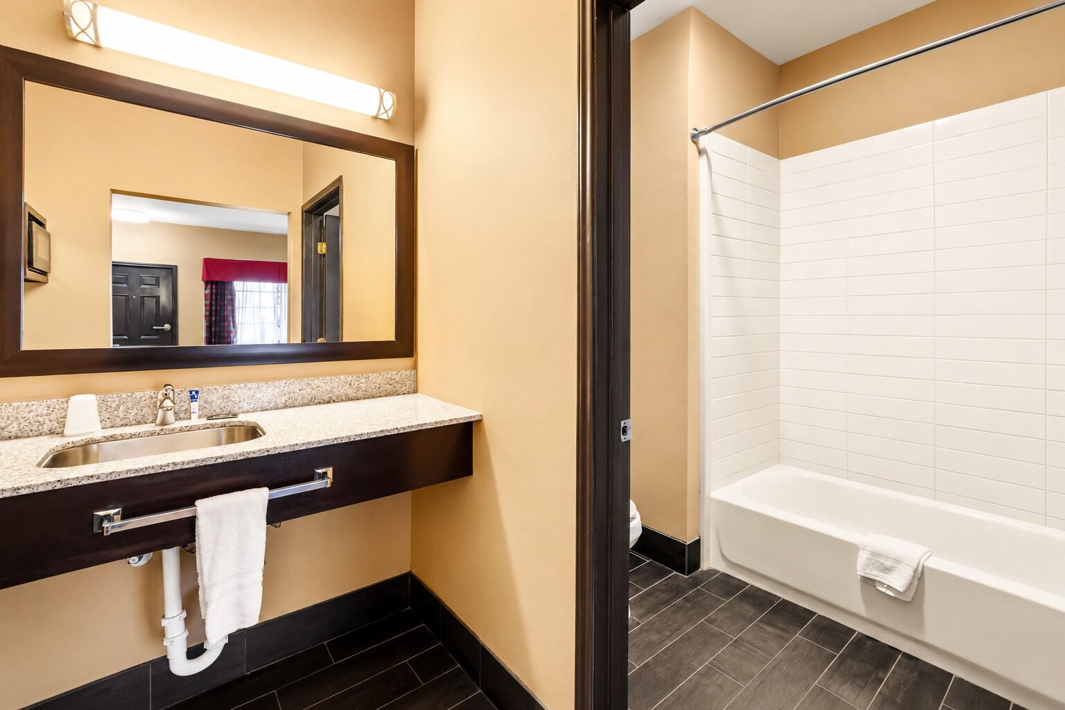 A hotel bathroom with a sink, mirror, and bathtub.