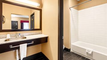 A hotel bathroom with a sink, mirror, and bathtub.