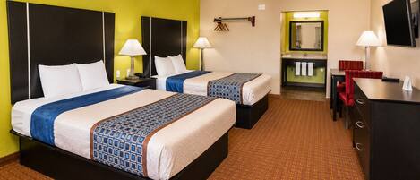 A hotel room with two beds, a desk, a chair, a TV, and a bathroom visible through an open door.
