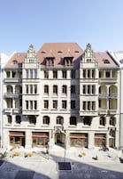 Een historisch gebouw met meerdere verdiepingen, grote ramen en balkons. Het heeft een traditionele architectuur met decoratieve details.