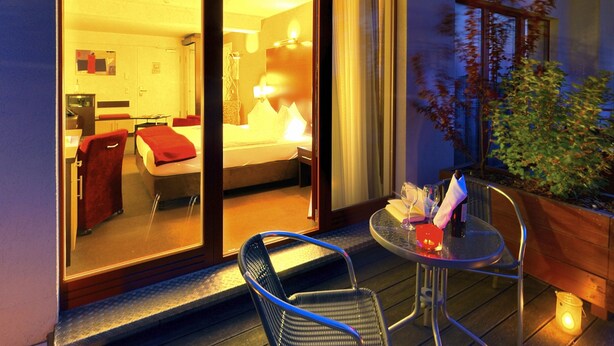 Une chambre d’hôtel dotée d’une porte-fenêtre coulissante donnant sur un balcon avec une table et des chaises.