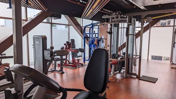 Un gimnasio con diverso equipo de ejercicio, incluyendo cintas de correr y máquinas de pesas.