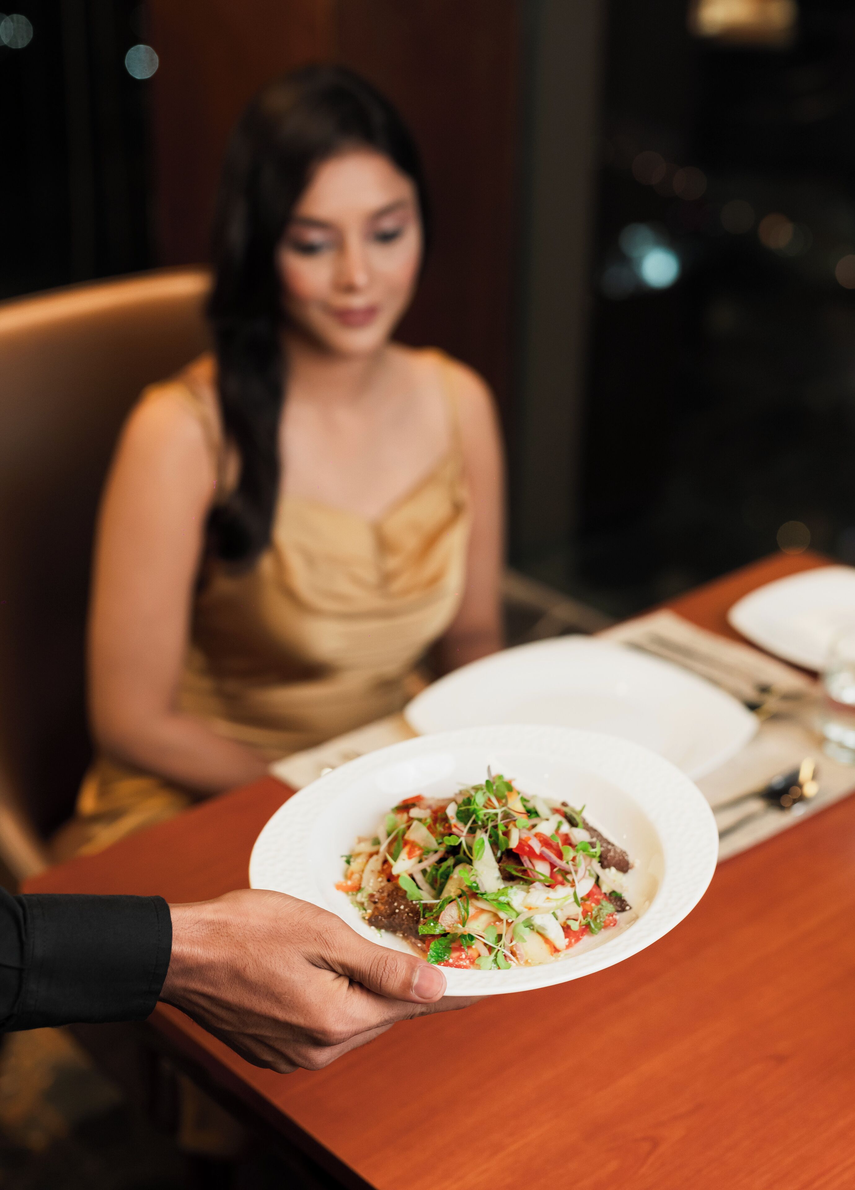 Una persona sosteniendo un plato de comida en una mesa de restaurante.