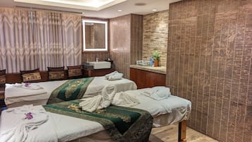 Relax in this serene spa room with a large bed, two additional beds, a wooden bench, and a potted plant.