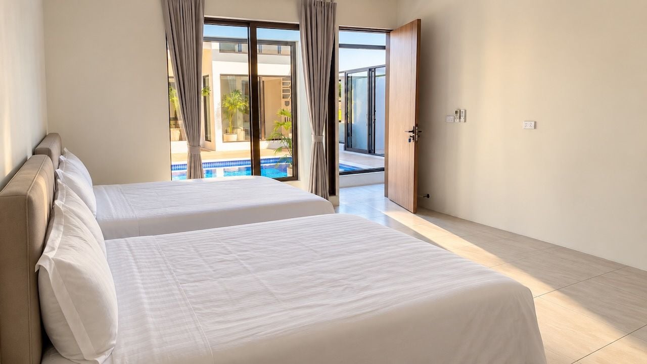 A hotel room with two beds, a view of a swimming pool, and a sliding glass door leading to an outdoor area.