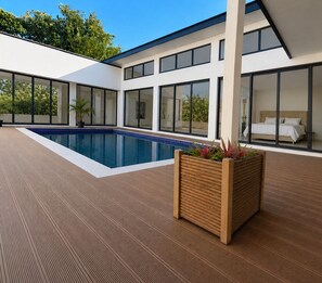 A modern pool area with a rectangular pool, wooden deck, and a planter with plants. - Sapphire Bay Fiji (Lautoka)