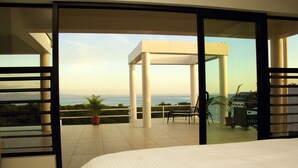 A bedroom with a balcony, a bed, a chair, and a table. - Sapphire Bay Fiji (Lautoka)