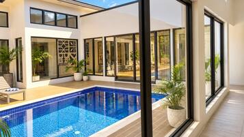 A modern house with a swimming pool, large windows, and outdoor furniture.