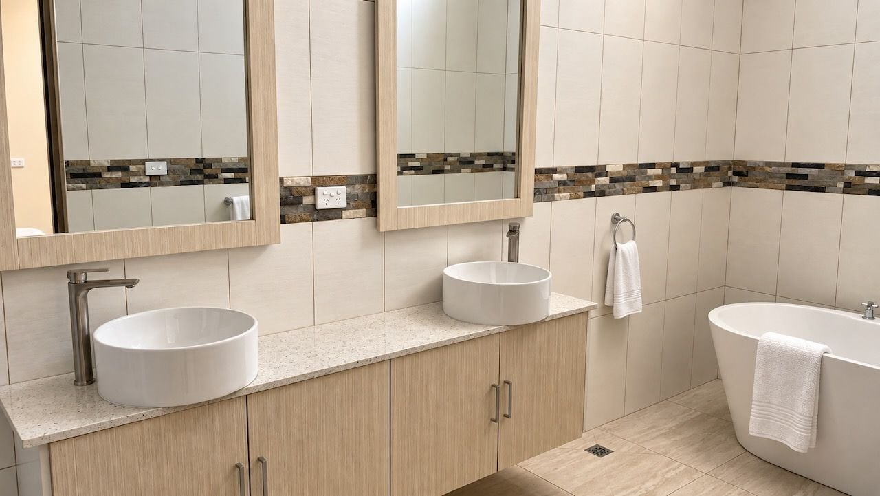 A modern bathroom with two sinks, a bathtub, and a large mirror.