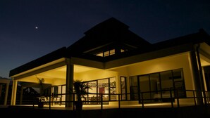 A modern building with a flat roof, large windows, and a covered outdoor area at dusk. - Sapphire Bay Fiji (Lautoka)