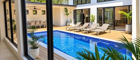 A modern house with a swimming pool, outdoor seating, and large windows.