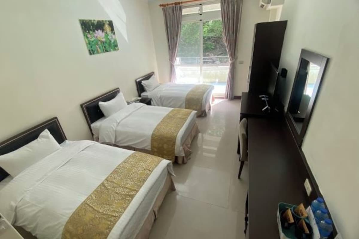 A hotel room with two beds, a TV, and a desk.