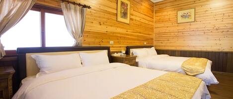 A hotel room with two beds, wooden paneling on the walls, and a window with curtains.