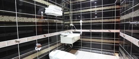 A modern bathroom with black and white tiles, a white sink, and a toilet.