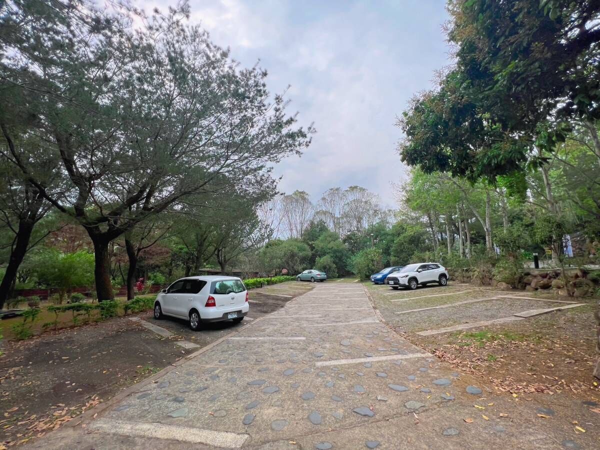 A parking area with multiple cars, surrounded by trees and greenery.
