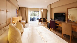 A hotel room with a large bed, a desk with a TV, and a dining area with chairs and a table. - Villa Caemilla Beach Boutique Hotel (Boracay Island)