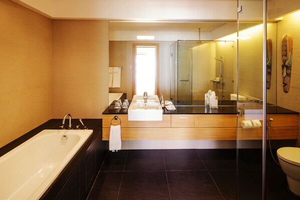 Ein modernes Badezimmer mit einer großen Badewanne, einer gläsernen Dusche und einem Waschtisch mit Spiegel.