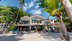 Villa Caemilla, a two-story building with a white facade and red roof, featuring outdoor seating and a covered patio area. - Villa Caemilla Beach Boutique Hotel (Boracay Island)