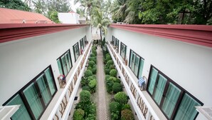 A hotel corridor with a central pathway flanked by neatly trimmed bushes and a series of windows on either side. - Villa Caemilla Beach Boutique Hotel (Boracay Island)