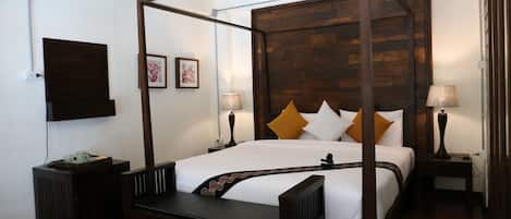 A four-poster bed with a wooden headboard, a bedside table with a lamp, and a small bedside table with a lamp.