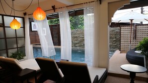 Ein Zimmer mit Blick auf ein Schwimmbad, einen Tisch und Stühle.