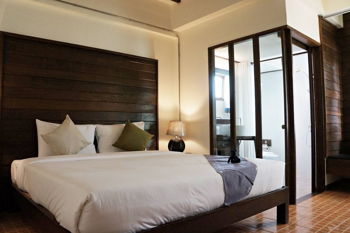 Un dormitorio con una cama grande, una mesita de noche, una lámpara y un cabecero de madera.