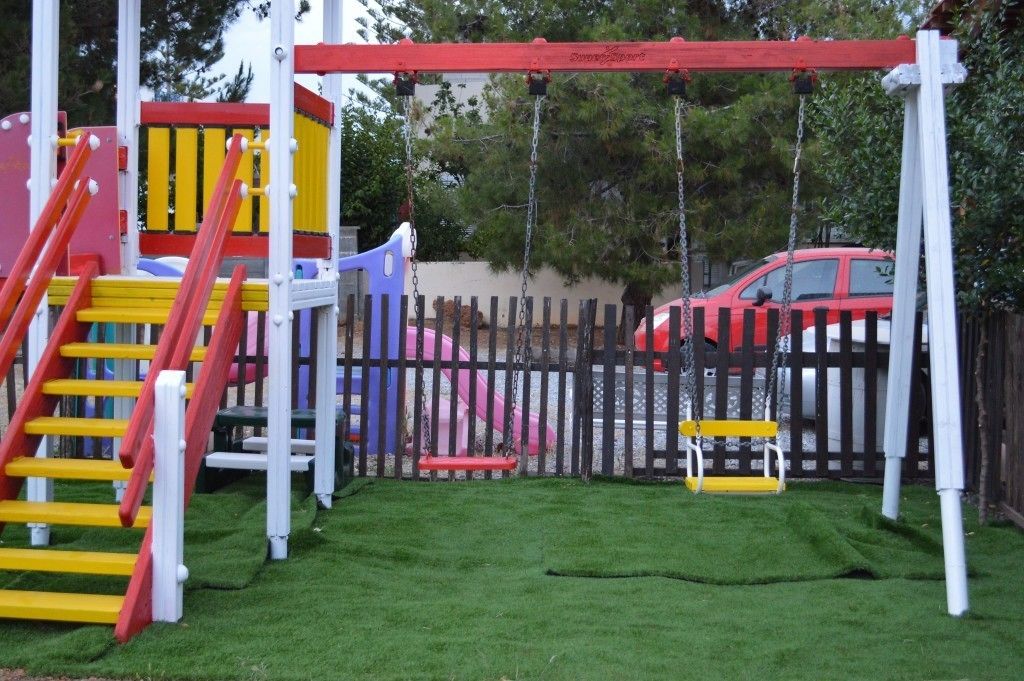 Een speeltuin met een schommel, een glijbaan en een klimstructuur.