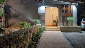 A modern house with a stone retaining wall, a brick pathway, and a car parked in the driveway.