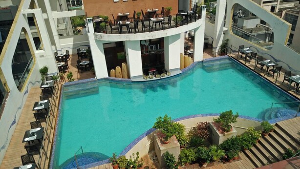 Una piscina al terrat amb diverses zones d'estar i un bar.
