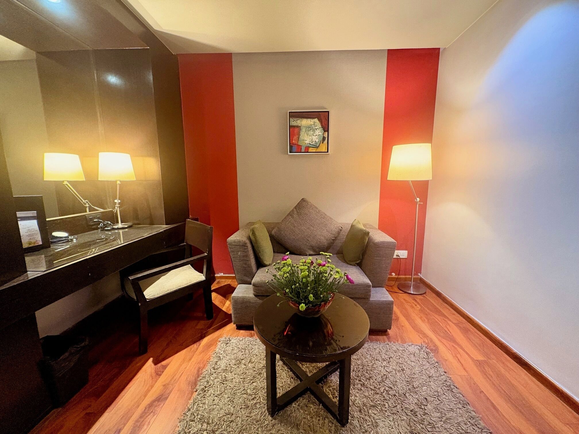 A modern living room with a sofa, a small table with a plant, a piano, and two lamps.