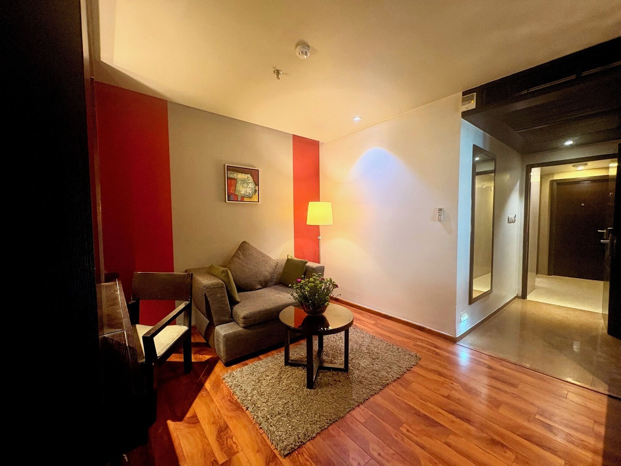 Una sala de estar moderna con un sofá, una mesita con una planta y una lámpara.