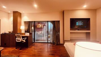 A hotel room with a wooden desk, chair, and a television on the wall.