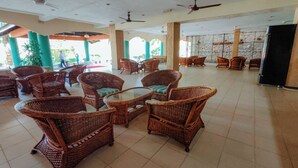 A spacious indoor area with wicker furniture, ceiling fans, and a stone wall in the background. - Virgo Batik Resort Teluk Batik Lumut (Lumut)