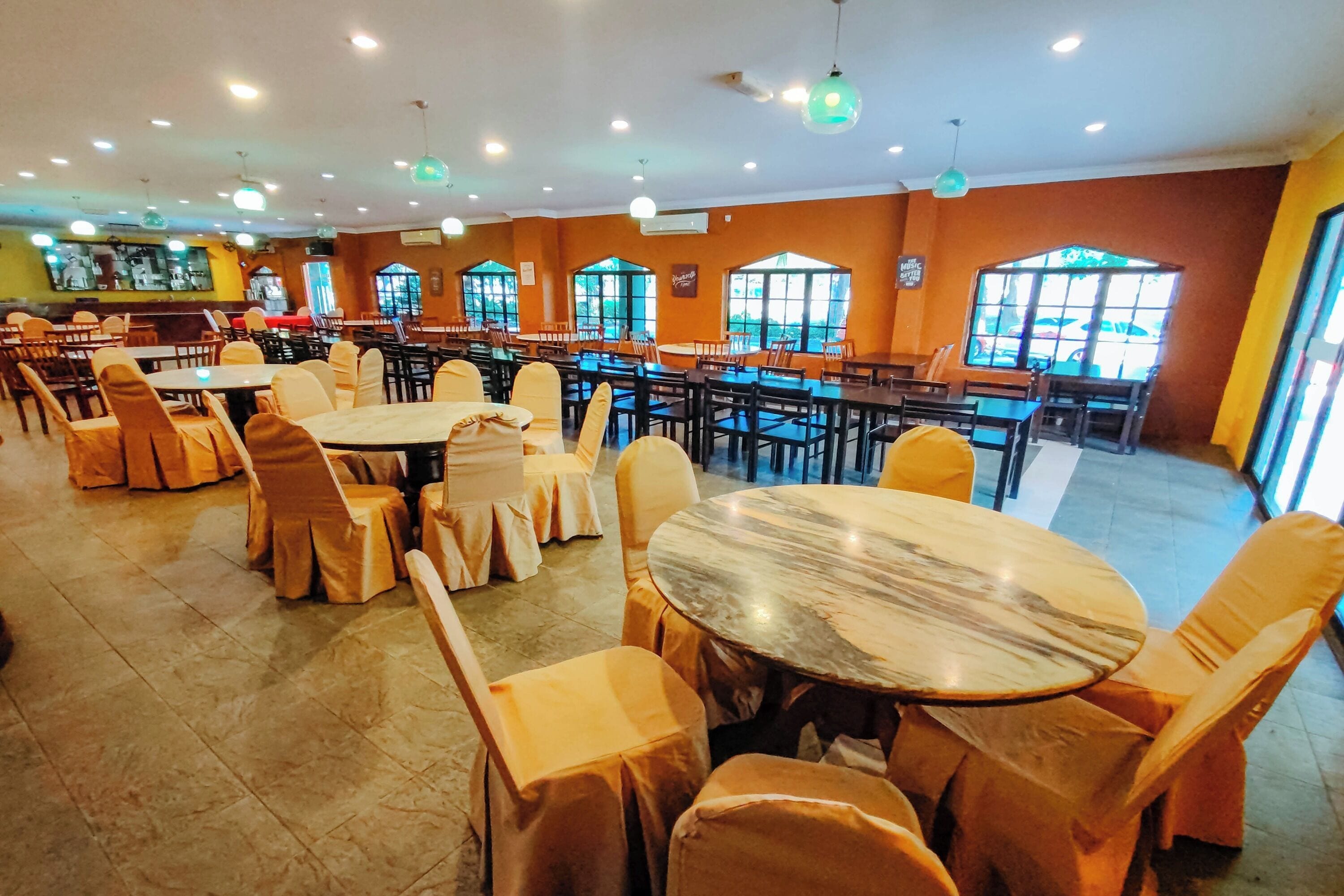 A restaurant with multiple tables and chairs, large windows, and a tiled floor.