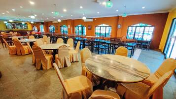 A restaurant with multiple tables and chairs, large windows, and a tiled floor.