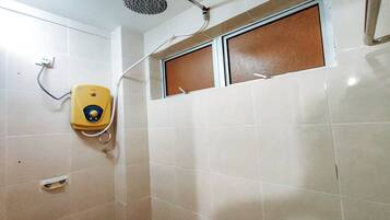 Un baño con inodoro amarillo, cabezal de ducha y ventana con persiana marrón.