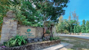 A stone wall with a sign for 'Virgo Bali Resort' surrounded by greenery and trees. - Virgo Batik Resort Teluk Batik Lumut (Lumut)